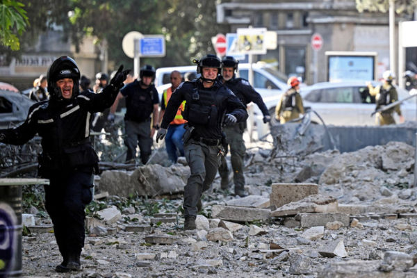 Tim penyelamat bekerja di lokasi bangunan yang hancur setelah serangan rudal dari Iran di Haifa, Israel, Minggu (22/6/2025). Foto: Florion Goga/REUTERS