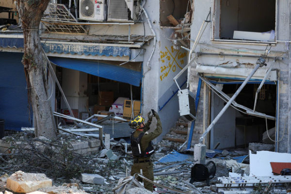 Tim penyelamat bekerja di lokasi bangunan yang hancur setelah serangan rudal dari Iran di Haifa, Israel, Minggu (22/6/2025). Foto: Florion Goga/REUTERS