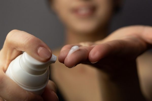 Close-up of a person applying cream to their face.