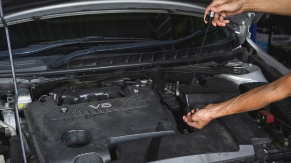 A person using a dipstick to check their transmission fluid level