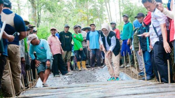 PERBAIKAN JALAN - Bupati Lumajang, Indah Amperawati Masdar terlihat meratakan semen di pembangunan jalan rusak yang dilakukan warga Sumbermujur Candipuro Lumajang, Sabtu (14/6/2025). Pemkab Lumajang menyerahkan bantuan material untuk aksi warga tersebut.