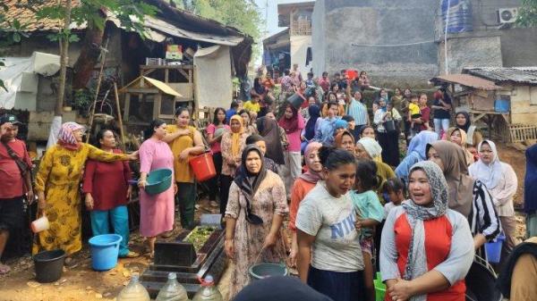 Warga Kampung Kiarajaya, Desa Margamulya, Kecamatan Telukjambe Barat, Kabupaten Karawang, antre ambil air bersih di sumur tengah area pemakaman pada Jumat (27/6/2025).