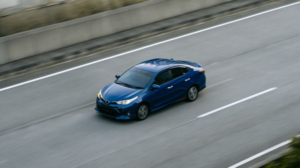 Blue Toyota compact car on a highway, high angle, front 3/4 view