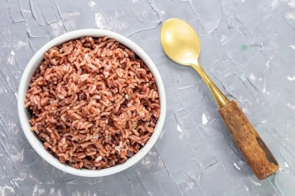 Rice red in bowl isolated on blue grey background has spoon close up, top view, Asian food and drink concept.