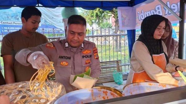 BANTU ORANG TUA - Bripka Antoni Wahyudi, ditemani isterinya menjual mi caluk di pusat pasar Keude Bambi, Kecamatan Peukan Baro, Kabupaten Pidie, Aceh, Selasa (4/3/2025).