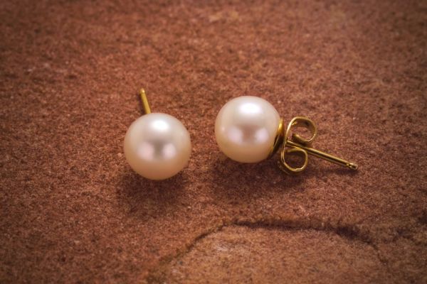 Close-up of pearl stud earrings with gold posts.