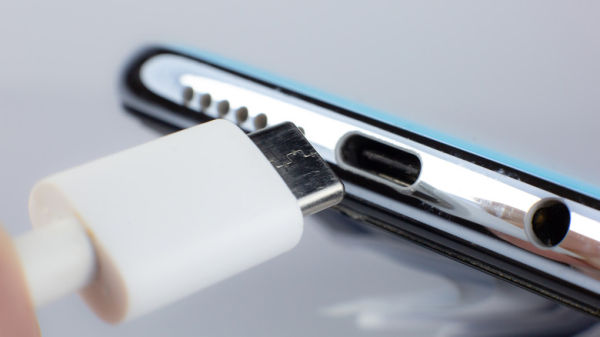A USB-C connector is about to be plugged into a smartphone.