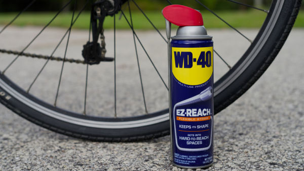 A can of WD-40 with a bicycle wheel in the background