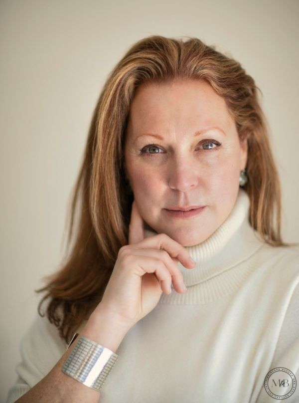 Portrait of a woman wearing a white turtleneck and silver bracelet.
