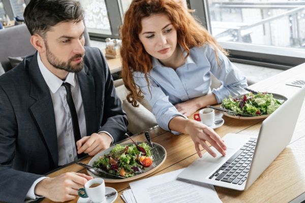 Businesspeople having lunch and working on a laptop.