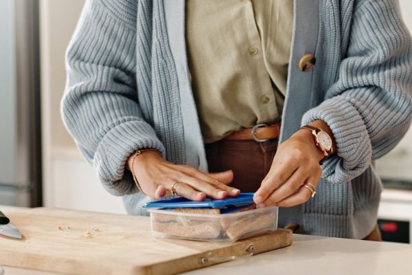 Person packing sandwiches in a plastic container.