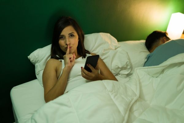Woman in bed secretly texting on her phone.