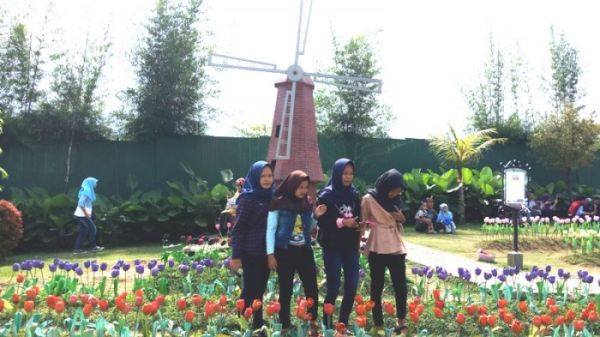 Pengunjung foto di depan bangunan berbentuk minatur kincir angin di Small World, Banyumas, Minggu (17/6/2018).