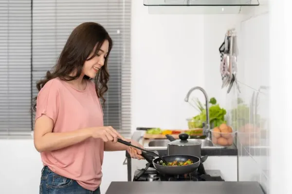 happy young woman cooking and preparing food in the kitchen at home