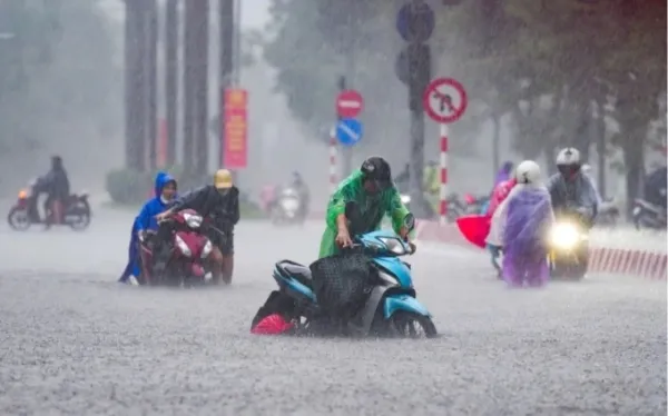 Residents pushed their motorbikes through heavy rain as floodwaters rose to around 0.4 meters on Nguyen Hoang Street, Hanoi. Photo by Tung Dinh