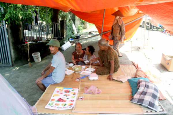 Ms. Chung (sitting on the board) and Ms. Thom (next to her) ate charity meals under a tarpaulin, on Do Tan dike, Trung Gia commune, noon October 12. Photo: Phan Duong