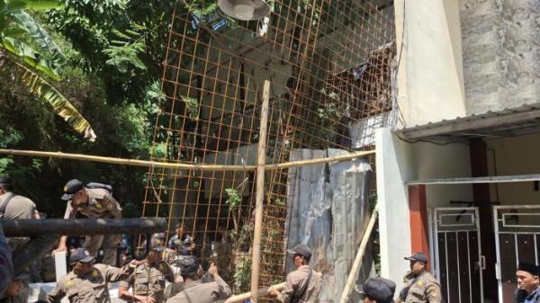 ARI PASRAH - Suasana pembongkaran pagar di Jalan Sinar Mas VII, Kelurahan Kedungmundu, Kecamatan Tembalang, Kota Semarang, Rabu (16/10/2025). Terlihat Ari pasrah sembari merangkul istri dan sesekali merekam kegiatan pembongkaran tersebut.