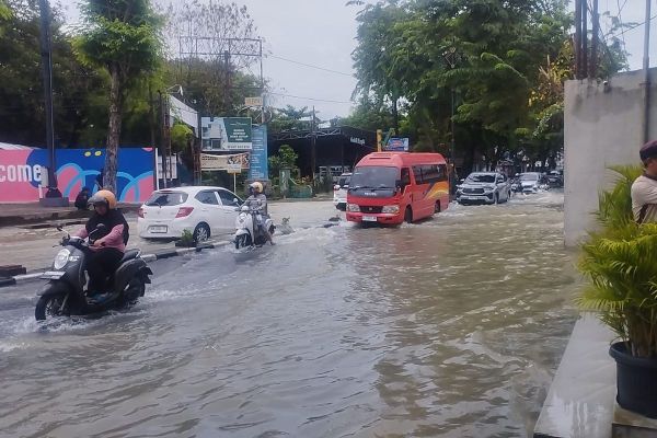 Pengendara terlihat menerobos genangan air yang menutup Jalan Dr Mansyur, Kelurahan Padangbulan, Kecamatan Medan Selayang, Minggu (12/10/2025).
