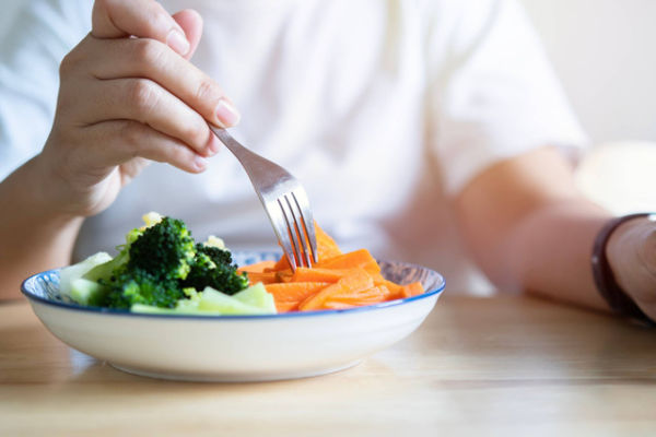 Ilustrasi perempuan makan wortel. Foto: Kunlathida6242/Shutterstock
