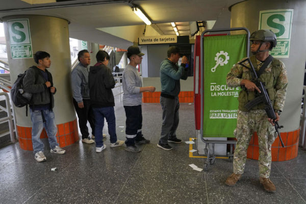 Pejalan kaki melintas di depan tentara yang berjaga di Lima, Peru, Rabu (22/10/2025). Foto: Martin Mejia/AP PHOTO