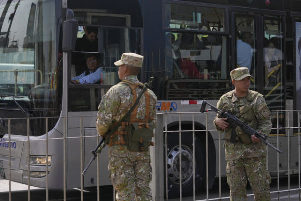 Seorang sopir bus melongok melalui jendela busnya untuk melihat tentara yang berjaga di Lima, Peru, Rabu (22/10/2025). Foto: Martin Mejia/AP PHOTO