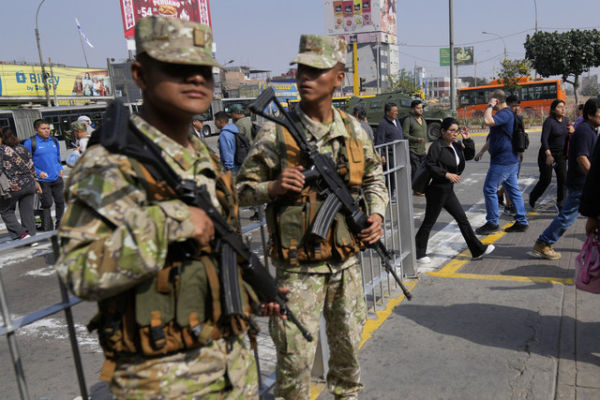 Pejalan kaki melintas di depan tentara yang berjaga di Lima, Peru, Rabu (22/10/2025). Foto: Martin Mejia/AP PHOTO