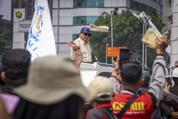 Presiden Republik Indonesia Prabowo Subianto membagikan kaos dari Mobil Maung saat meninggalkan perayaan May Day di kawasan Monas, Jakarta, Kamis (1/5/2025). Foto: Iqbal Firdaus/kumparan