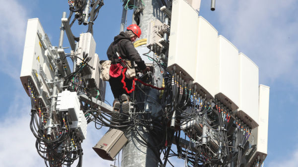 A worker rebuilds a cellular tower with 5G equipment for the Verizon network