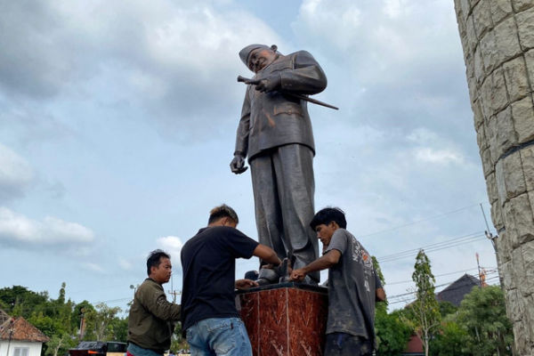Petugas menurunkan patung Soekarno yang kepalanya terlihat miring, di Alun-alun Kabupaten Indramayu. Foto: kumparan