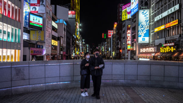 Sejumlah orang berdiri di jembatan penyeberangan di daerah Dotonbori di Osaka, Jepang. Foto: Philip FONG/AFP