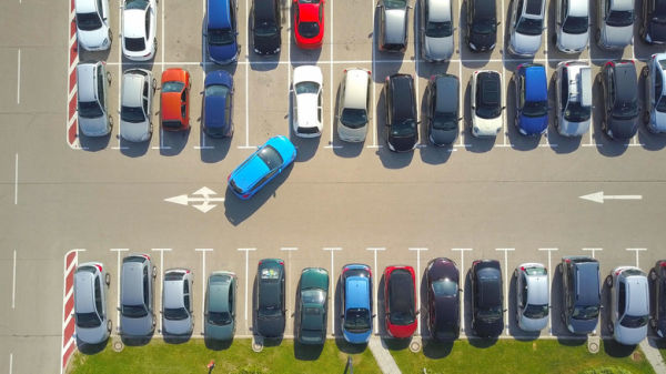 Aerial top-down view of parking lot showing car pulling into a spot