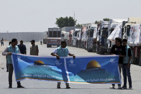 Tiga sopir truk membentangkan spanduk saat membawa bantuan memasuki Mesir dari Gaza melalui pos perbatasan Rafah di Rafah, Mesir, Rabu (6/8/2025). Foto: Amr Abdallah Dalsh/Reuters