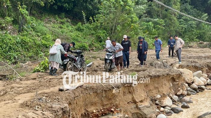 JALAN PUTUS- Penampakan kendaraan masyarakat yang terpaksa melewati jalan berlumpur dan licin di kawasan Batu Busuk, Kelurahan Lambung Bukit, Kecamatan Pauh, Kota Padang terjatuh, Jumat (12/12/2025). 