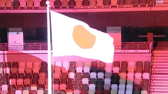 Bendera Jepang dikibarkan saat upacara Pembukaan Olimpiade Tokyo, Jumat (23/7/2021) malam. Tampak kursi penonton kosong.