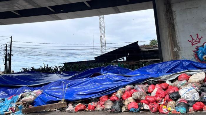 DARURAT SAMPAH - Gunungan sampah di Jalan Dewi Sartika, tepatnya kolong Flyover Ciputat, Tangsel pada Rabu (17/12/2025). Pengamat Kebijakan Publik, Trubus Rahardiansyah menegaskan langkah pemkot tangsel yang menutup gunungan sampah dengan menggunakan terpal bukanlah solusi.