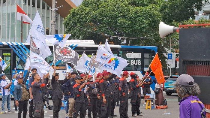 Massa buruh menggelar unjuk rasa di Jalan Medan Merdeka Selata dekat Kawasan Patung Kuda, Jakarta. Mereka menyanyikan lagu Internasionale sebagai penutup aksi, Senin (229/12/2025).