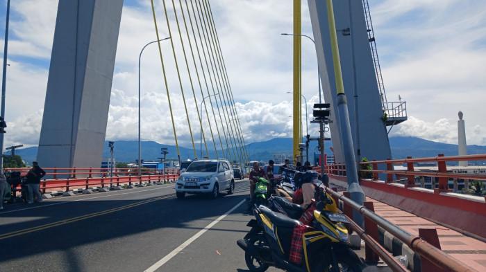 JEMBATAN SOEKARNO - Warga mengunjungi Jembatan Soekarno, Manado, Sulawesi Utara, Kamis (1/1/2026). Mereka berfoto hingga makan es krim.