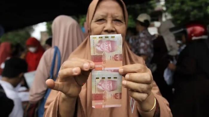 BANSOS 2026 - Warga menunjukkan uang tunai saat penyaluran bantuan sosial di Lapangan Sejati, Medan, Senin (24/11/2025). PKH, Bansos Sembako, hingga PIP adalah sejumlah bansos yang akan cair pada tahun 2026.