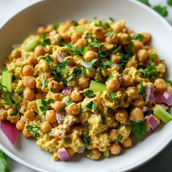 This may contain: a white bowl filled with chickpeas and garnished with cilantro