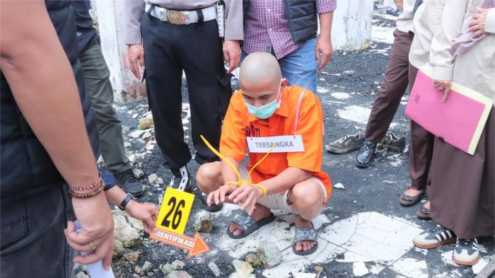 REKA ADEGAN- Tersangka berinisial IM sedang memperagakan membuat perapian untuk menghangatkan badan dalam rekonstruksi kasus kebakaran Pasar Payakumbuh Blok Barat, yang digelar pada, Selasa (6/1/2026).