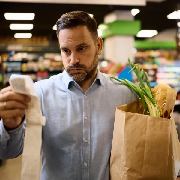 Dad looking at grocery bill deciding if he can afford school supplies