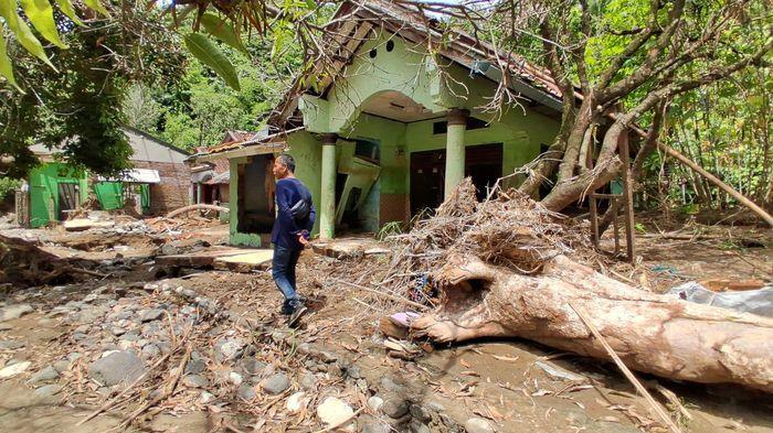 RUMAH RUSAK- Seorang pria berjalan di depan rumah warga di Kampung Babakan Cisarua, Sukabumi yang porak poranda oleh banjir bandang Sungai Cidadap, Kamis (8/1/2026).