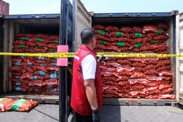 Anggota Ditreskrimsus Polda Jawa Timur menunjukkan barang bukti saat ungkap kasus pengiriman bawang bombay secara ilegal di salah satu lapangan penumpukan kontainer di kawasan Pelabuhan Tanjung Perak, Surabaya, Jawa Timur, Selasa (23/12/2025). Foto: ANTARA FOTO/Didik Suhartono