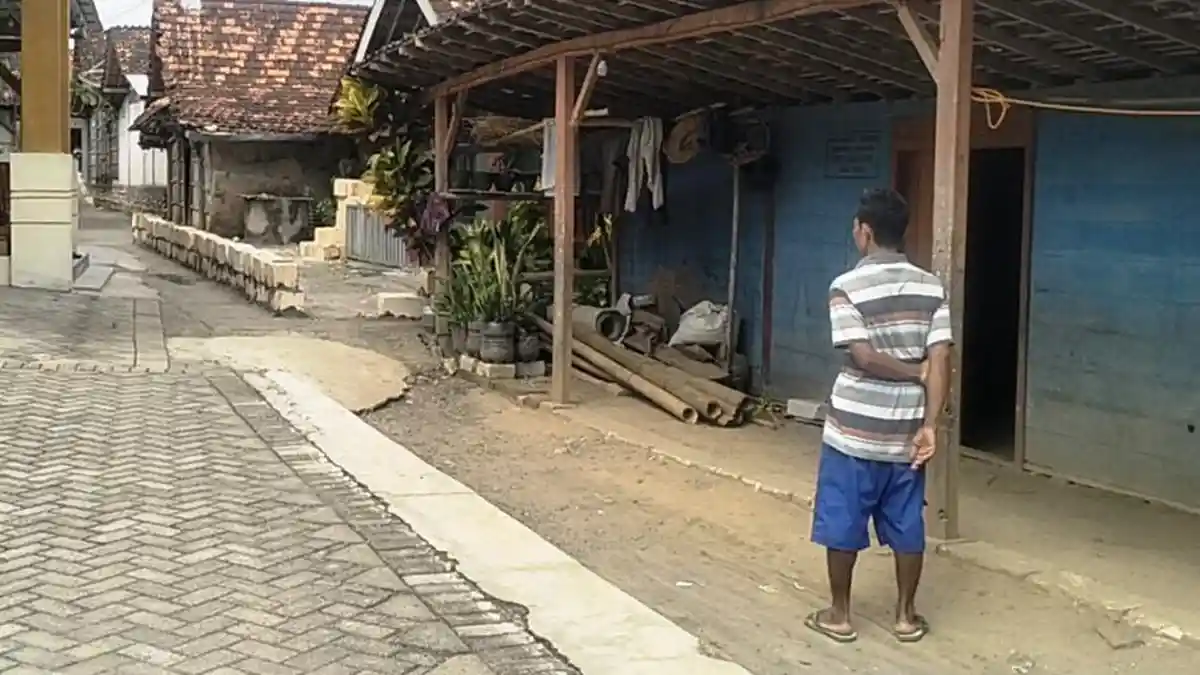 PONDASI BATU KUMBUNG - Sodikun melihat pondasi batu kumbung di RT 2 RW 3, Dukuh Ngudi, Desa Kalangan, Kecamatan Tunjungan, Kabupaten Blora, Kamis (8/1/2026). Akses warga menjadi terganggu seusai munculnya pondasi di tengah jalan. 