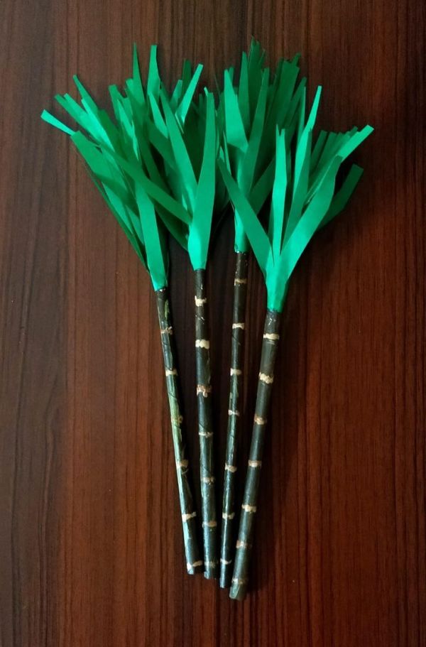 This may contain: three green paper flowers sitting on top of a wooden table