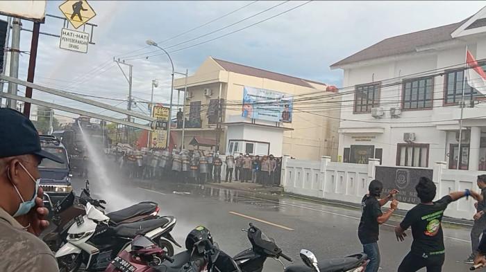Semprot Air - Polisi menyemprotkan water canon ke arah demonstran yang sedang menggelar aksi unjuk rasa di depan Polresta Mamuju pada Senin (12/6/2026).