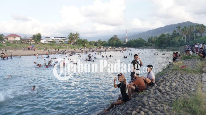 WISATA DADAKAN- Beberapa remaja laki-laki tengah bergaya saat dipotret di lokasi aliran sungai yang menjadi wisata dadakan kawasan Jembatan Ujung Tanah, Kecamatan Lubuk Begalung, Kota Padang, Senin (12/1/2026) sore.