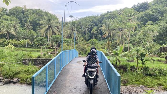 MELINTAS - Pengendara motor saat melintas di Jembatan Ngelo, Parakan, Sidomulyo, Pengasih, Kulon Progo, DI Yogyakarta, Selasa (13/1/2026).