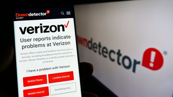 Verizon website on smartphone held alongside display showing Down Detector website
