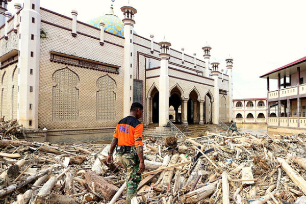 Prajurit TNI berjalan di atas tumpukan kayu di halaman Masjid Pesantren Islam Terpadu Darul Mukhlishin di Desa Tanjung Karang, Aceh Tamiang, Aceh, Jumat (19/12/2025). Foto: ANTARA FOTO/Irwansyah Putra